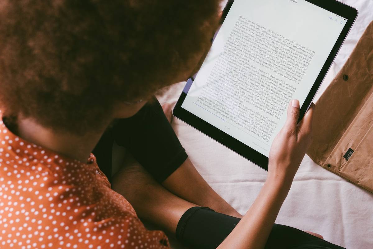 Une femme tenant une tablette et lisant